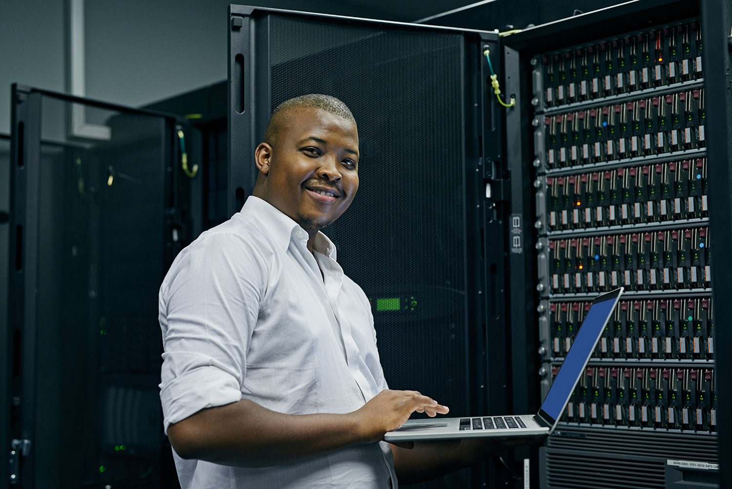 shot of an it technician using a laptop while working in a data